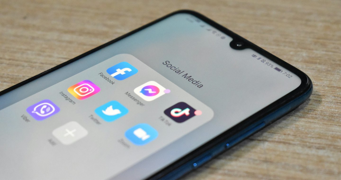 Smartphone showing social media apps on a wooden table.